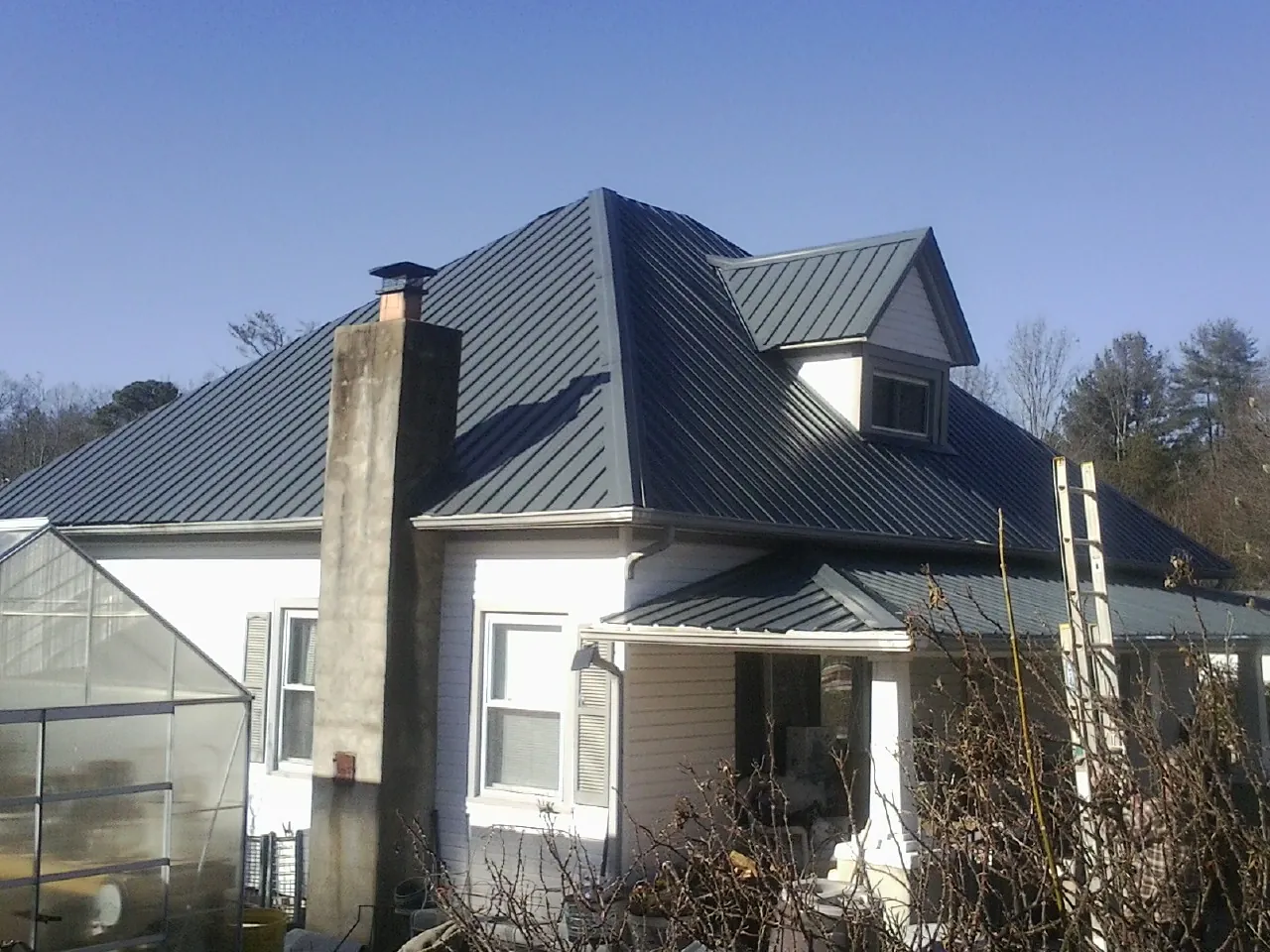 Dark blue standing seam metal roof on a white farmhouse with dormer — Slate & Tile Roof Repair by Roofing Brothers in Cave Junction