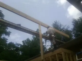 Carpenter setting a ridge beam over a new addition frame — Ice Dam Removal by Roofing Brothers in Cave Junction