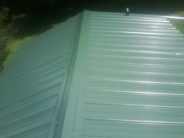 New green metal panels meeting at the ridge of a roof — Flat Roof Repair work by our crew in Cave Junction