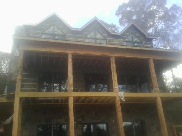 Dormers and porch framing on a large log home under construction — Roof Coating work by our crew in Cave Junction