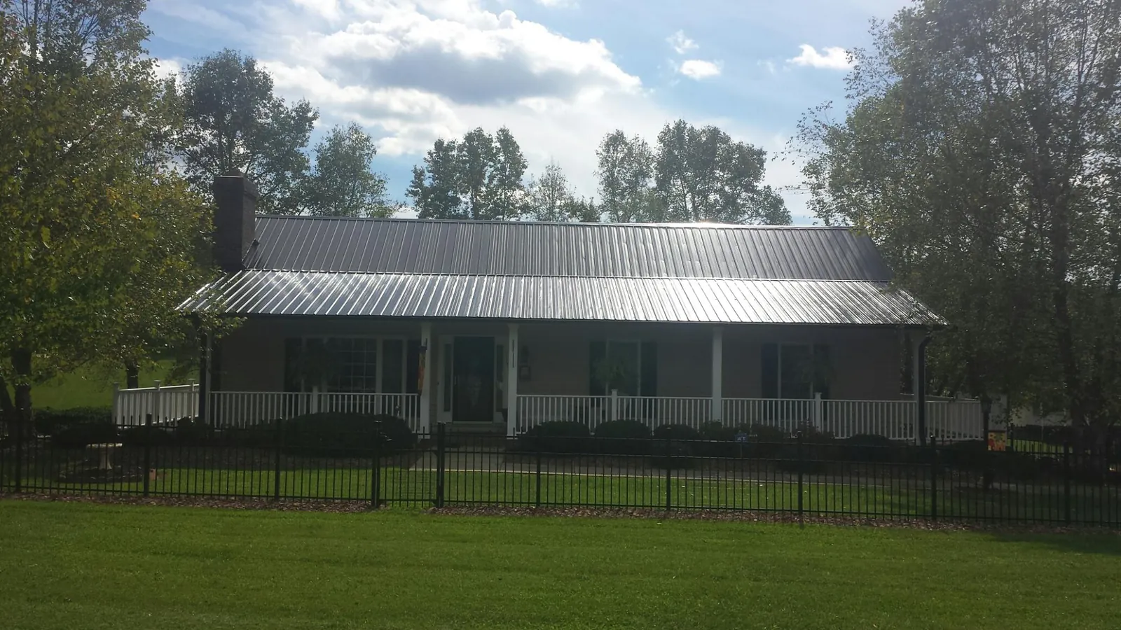 Gray metal roof on a brick ranch with a full width front porch — Gutter Guard Installation work by our crew in Cave Junction
