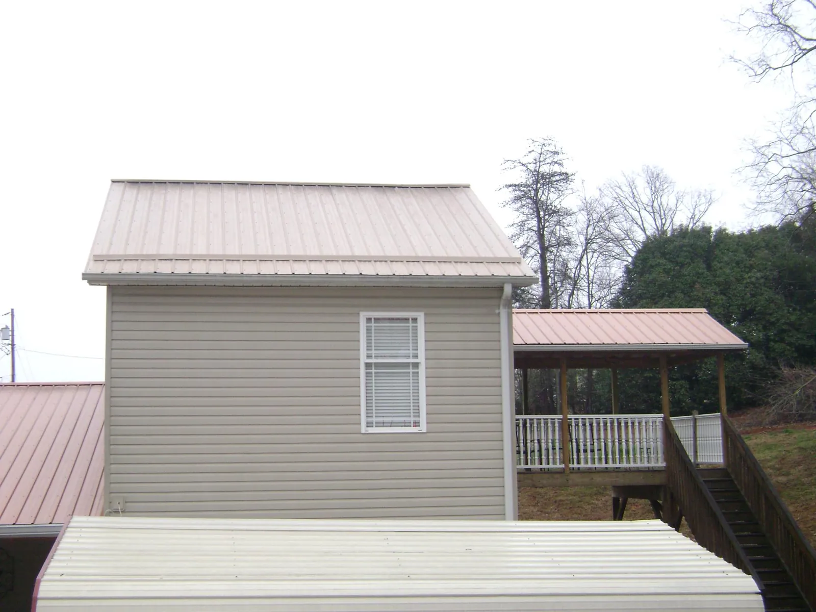 Tan metal roofs on a two story addition and attached porch, from a Roof Replacement job in Cave Junction