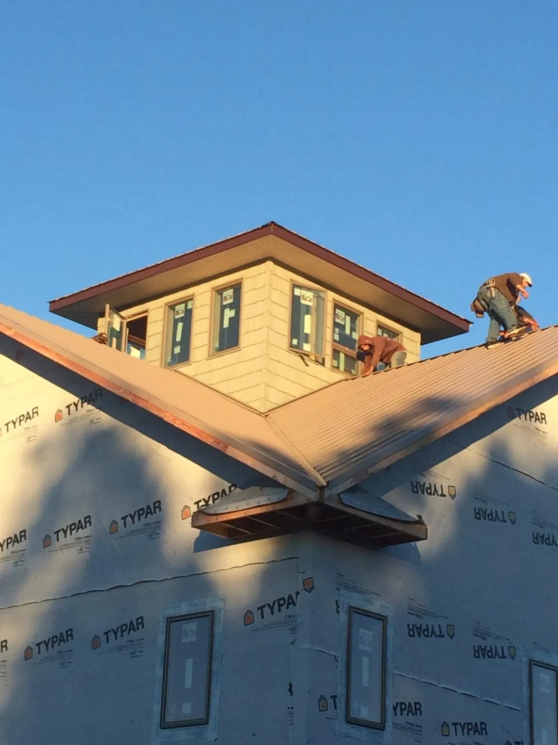 Roofers working around a rooftop cupola on a new metal roof at sunset — Roof Waterproofing in Cave Junction by Roofing Brothers